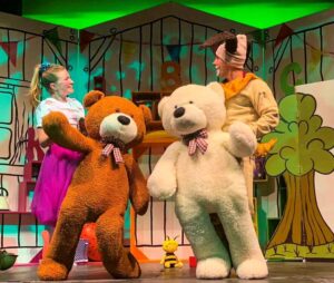 A close up of two actors on stage with near life size soft teddybear toys on the set of I Spy With My Little Eye